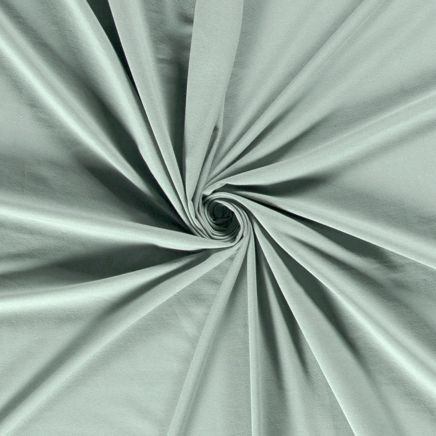Tissu jersey lisse et doux de couleur vert sauge, plié en spirale au centre pour montrer sa texture souple. - comment coudre du jersey avec une machine
