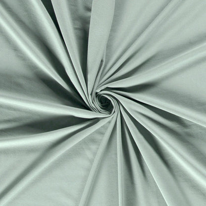 Tissu jersey lisse et doux de couleur vert sauge, plié en spirale au centre pour montrer sa texture souple. - comment coudre du jersey avec une machine